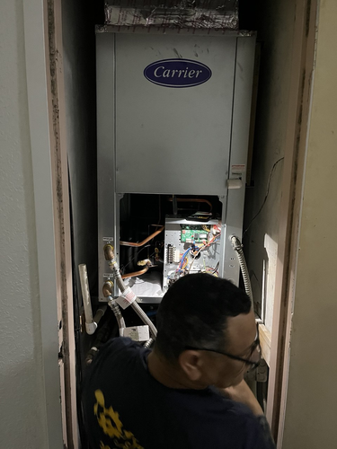 Professional technician servicing Carrier indoor HVAC unit